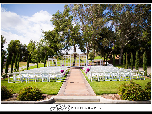 full view of outdoor wedding venue, with rows of white chairs, a brick aisle, and minimalist canopy